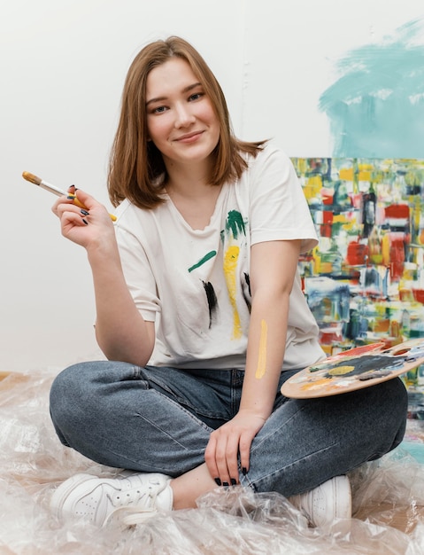 Young woman posing next to her colorful painting