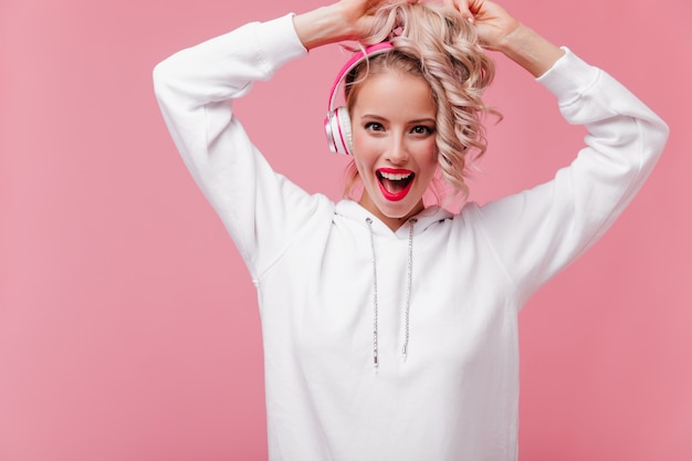 Young woman posing and listening to music through her pink headphones