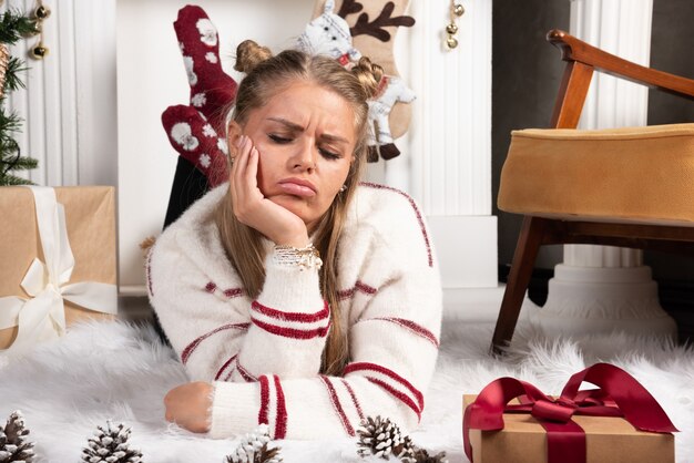 A young woman posing lying down on carpet in Christmas interior. 