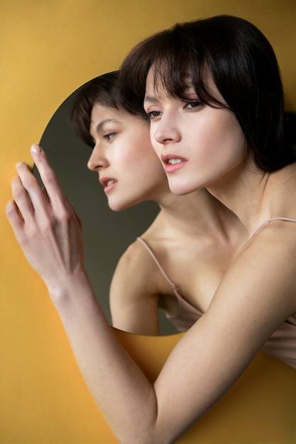 Молодая женщина позирует рядом с зеркалом, создавая отражение