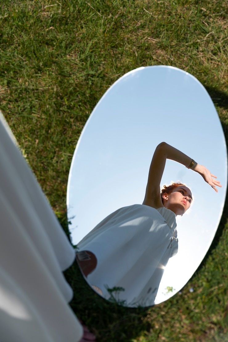 Free Photo young woman posing in the mirror on grass outdoors
