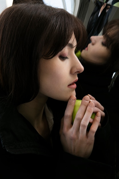 リンゴと鏡の横でポーズをとって若い女性
