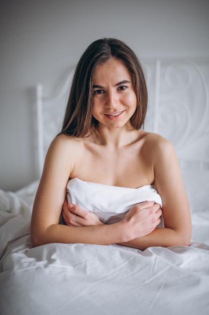 Young woman posing naked in bed