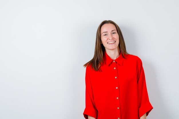 Young woman posing in red blouse and looking happy. front view.