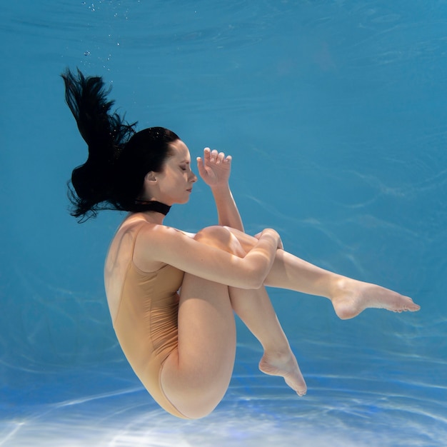 Young woman posing submerged underwater in a flowy dress