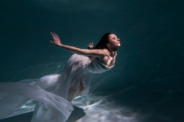 無料写真 流れるようなドレスを着て水中でポーズをとる若い女性