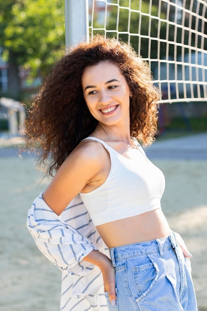 Free photo young woman posing next to a volleyball field