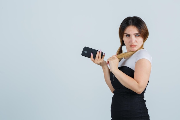 髪を整えて携帯電話を持ってポーズをとる若い女性