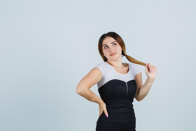 Giovane donna in posa mentre tiene una ciocca di capelli