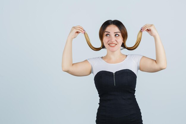 Young woman posing while holding strands of her hair