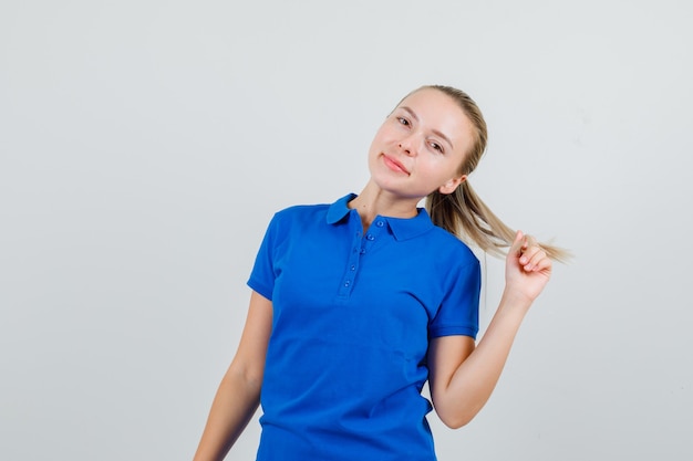 Молодая женщина позирует, глядя в синюю футболку и выглядя очаровательно