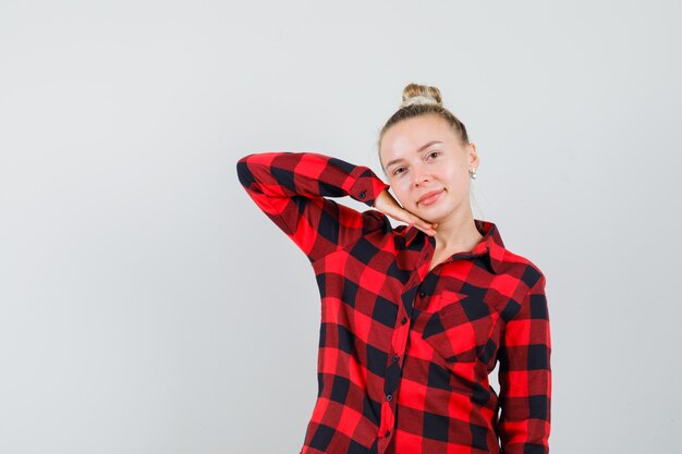 Young woman posing while standing in checked shirt and looking graceful