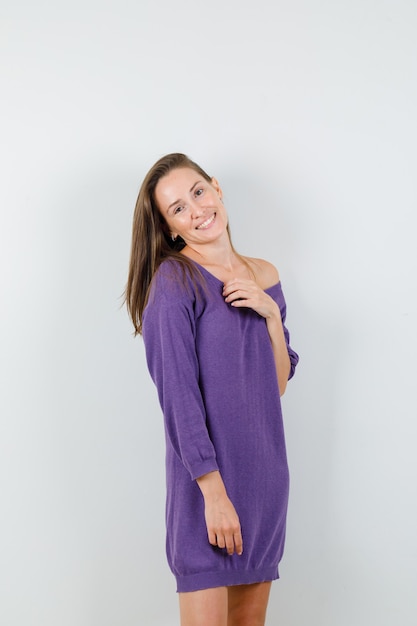 Young woman posing while standing in violet shirt and looking alluring. front view.