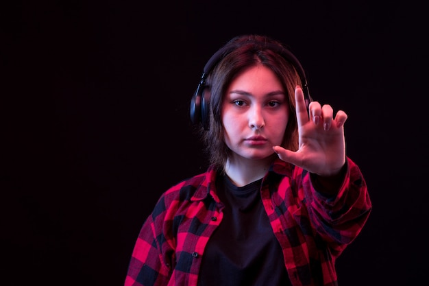 Free photo young woman posing wiht checkered red and black shirt using headphones