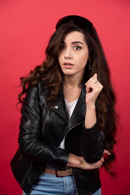 Young woman posing with black glasses on a red background. High quality photo