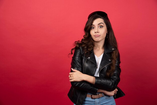 Young woman posing with crossed arms on a red background. High quality photo