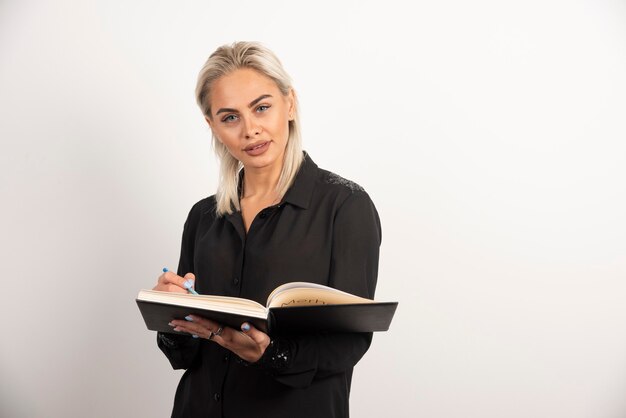 Young woman posing with a cup and clipboard on white background. High quality photo