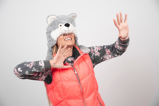 Young woman posing with funny hat on a white wall.