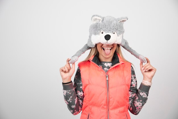 Young woman posing with funny hat on a white wall.