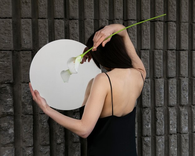 Young woman posing with mirror and flower