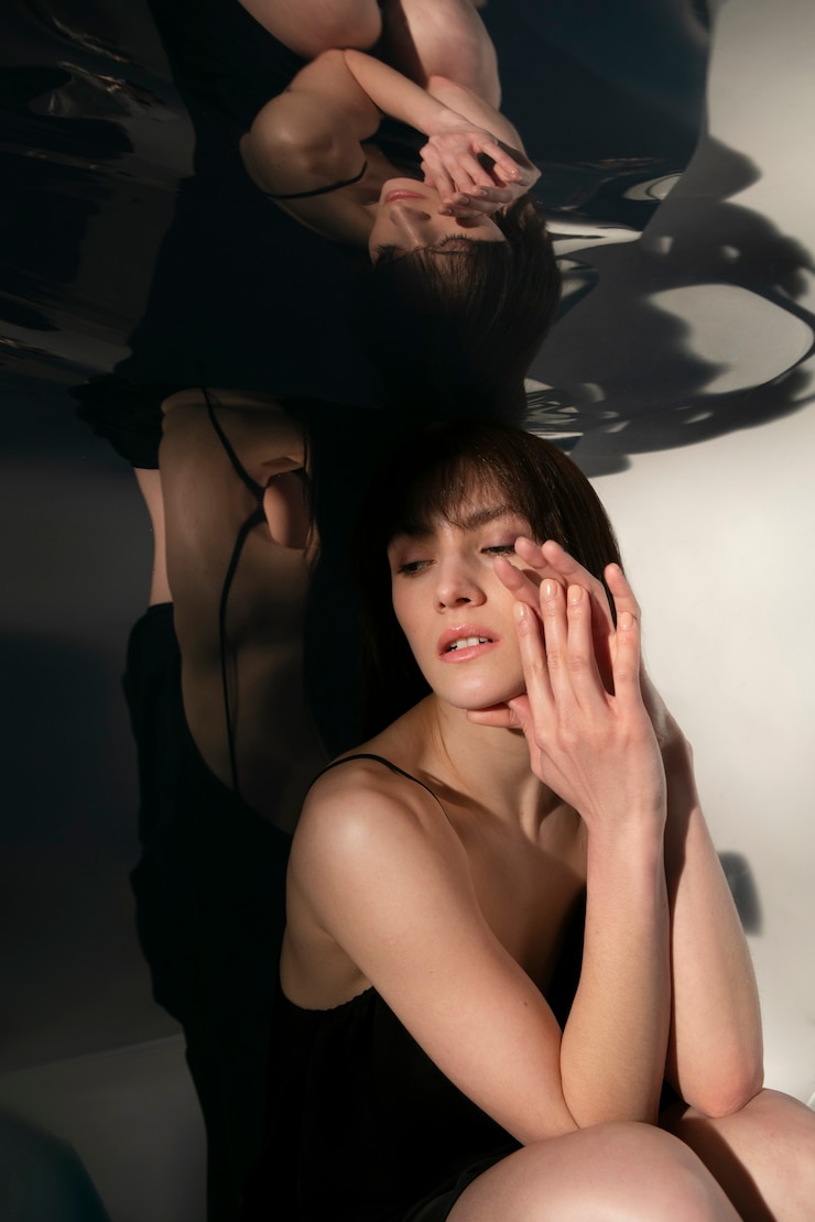 무료 Photo 젊은 여성이 거울 반사와 함께 포즈를 취하고 있습니다.