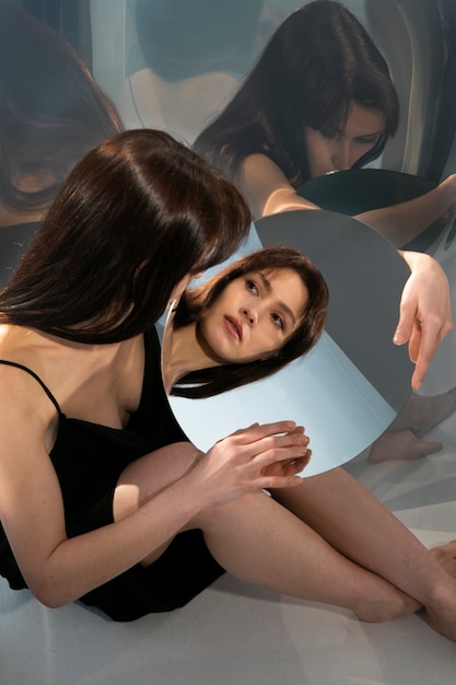 무료 사진 거울 반사와 함께 포즈를 취하는 젊은 여자