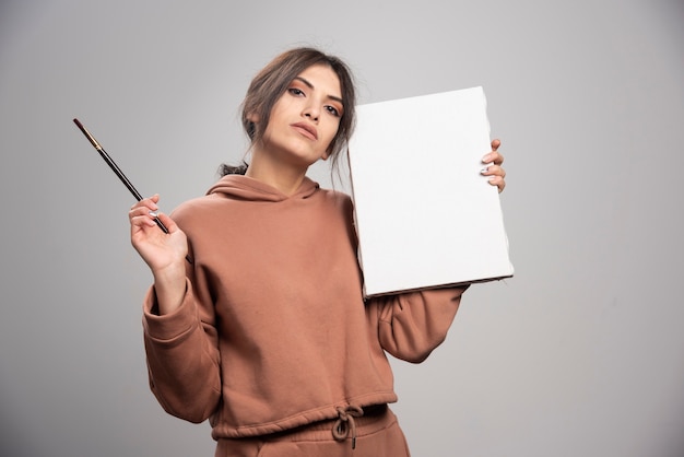 Young woman posing with paint brushes and canvas