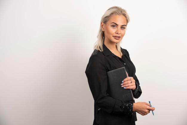 Young woman posing with a pencil and clipboard on white background. High quality photo