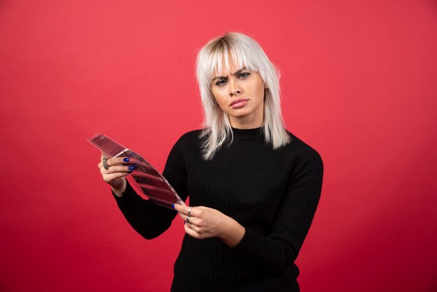 Young woman posing with a photo tape on a red background