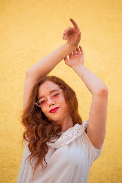 Foto gratuita giovane donna che posa con gli occhiali da sole