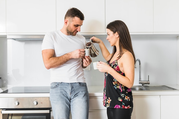 Молодая женщина наливает кофе в чашку держать ее парнем