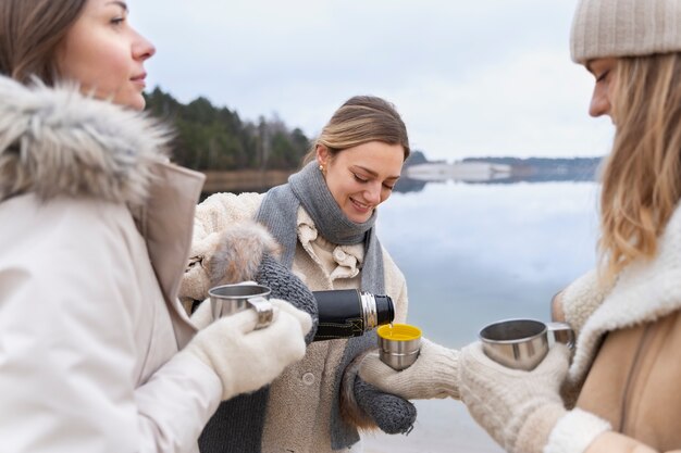 カップに友達に水を注ぐ若い女性