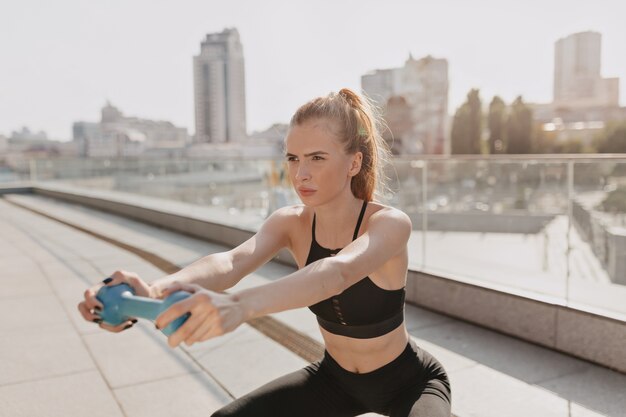 Young woman practice stretching outdoor with hand dumbbells in sunlight . High quality photo