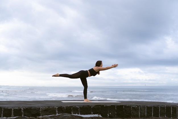 Young woman practice yoga on a beautiful beach at sunrise. Blue sky, ocean, waves, proximity to nature, unity with nature.