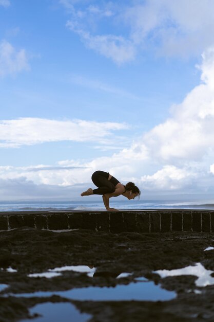 Young woman practice yoga on a beautiful beach at sunrise. Blue sky, ocean, waves, proximity to nature, unity with nature.