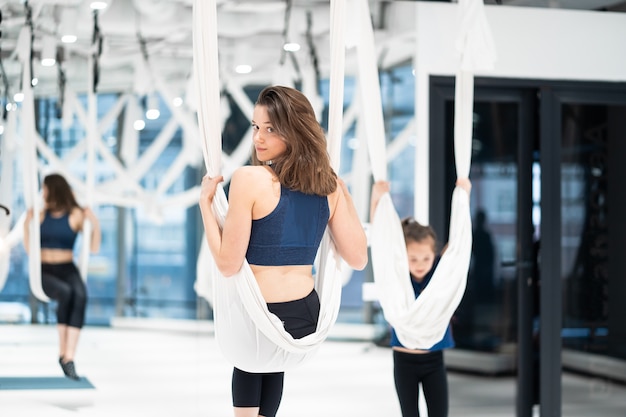 Young woman practices aerial anti-gravity yoga