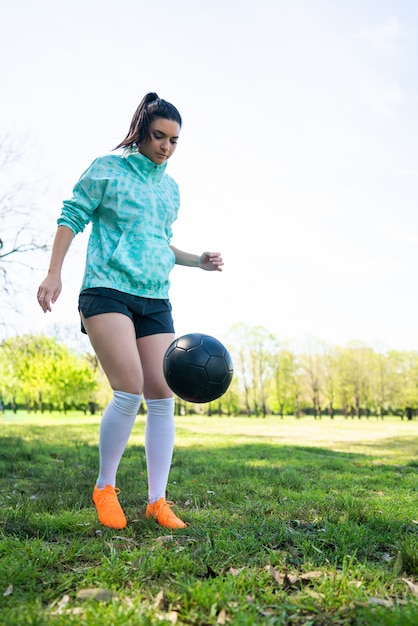 ボールでサッカーのスキルを練習する若い女性