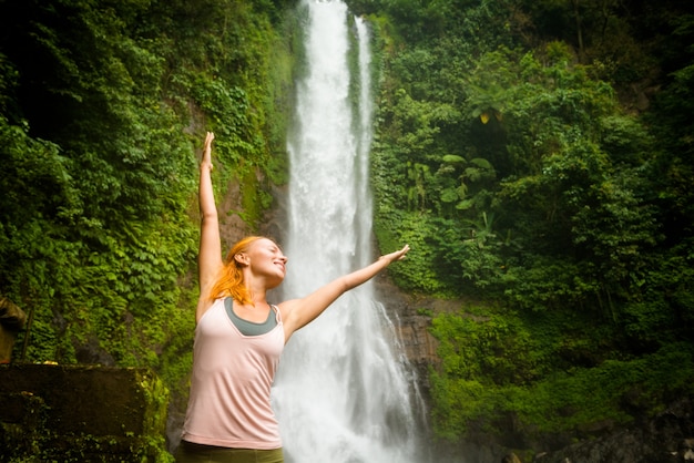 Young woman practicing yoga by the waterfall