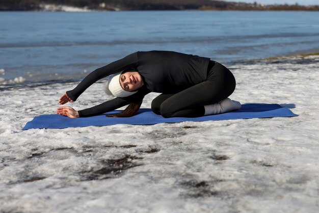 Young woman practicing yoga outdoors during winter on the beach
