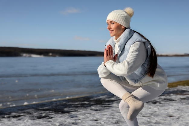 Young woman practicing yoga outdoors during winter on the beach