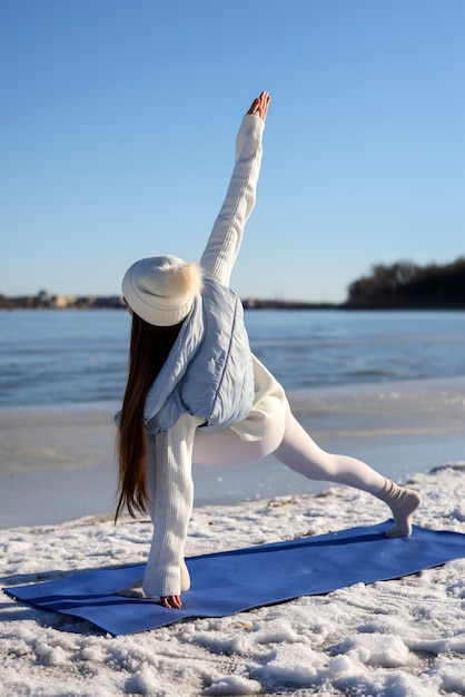 Young woman practicing yoga outdoors during winter on the beach