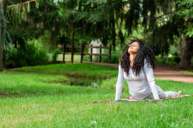 Young woman practicing yoga positions in the park surrounded by trees