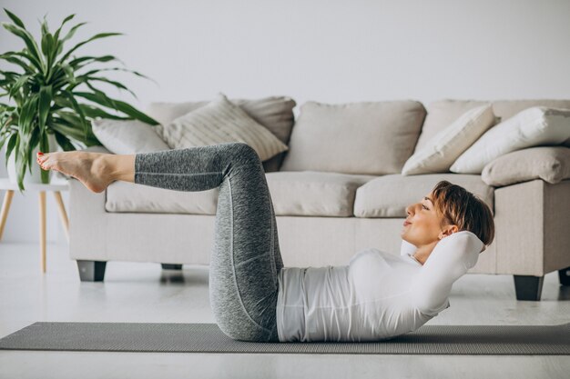 Young woman practising yoga at home on mat