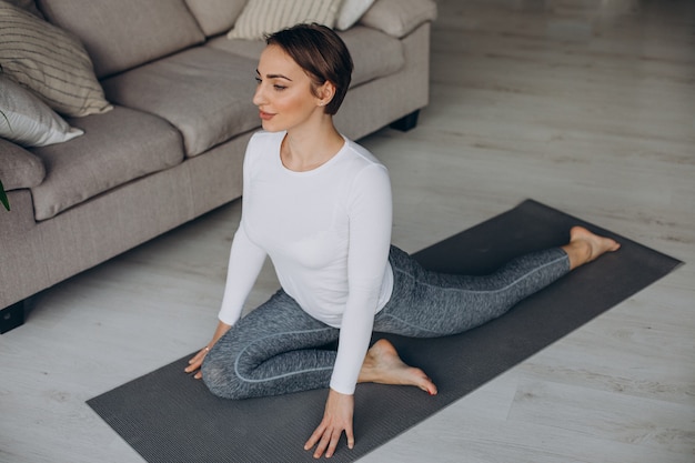 Young woman practising yoga at home on mat