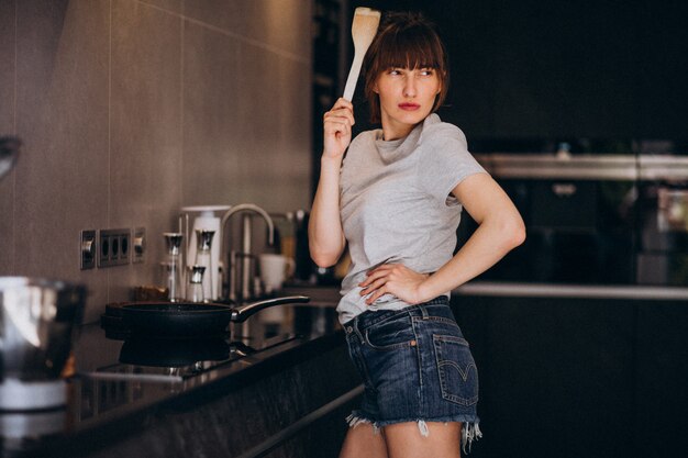 Free photo young woman preparing breakfast in kitchen in the morning