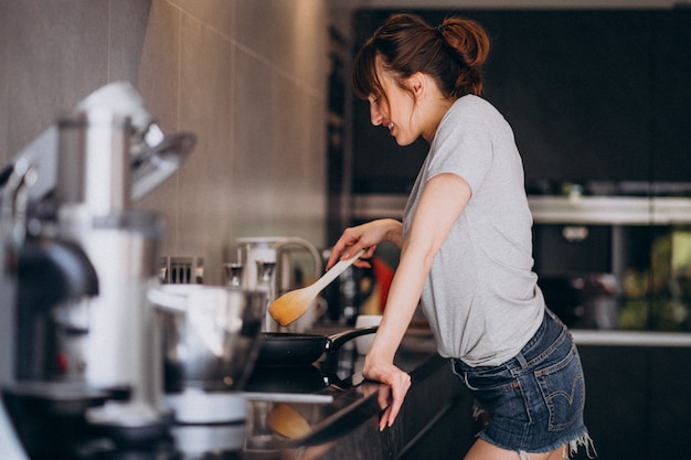 若い女性が朝の台所で朝食を準備します。