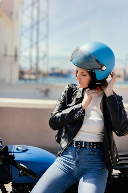 Foto gratuita giovane donna che si prepara a guidare in una moto in città