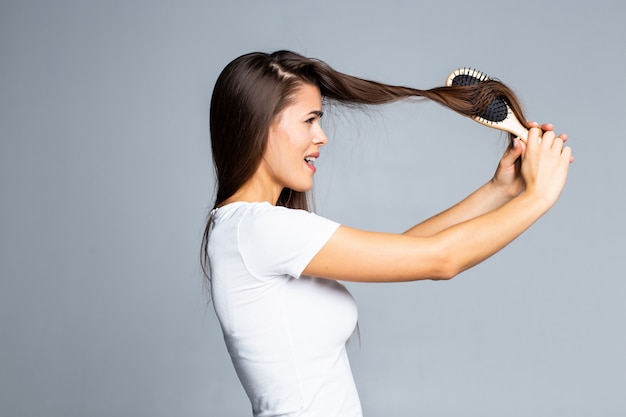 Young woman problems with hair, split weak hair, tangled hair isolated on gray