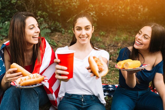 ホットドッグとドリンクを提案する若い女性