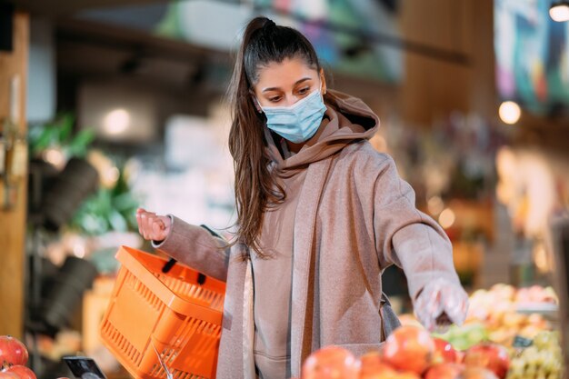 Молодая женщина в защитной маске делает покупки